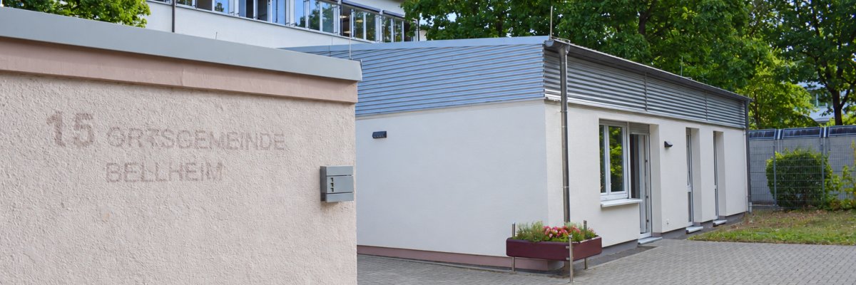 Gemeindehaus Bellheim mit modernem Anbau und gepflastertem Außenbereich.