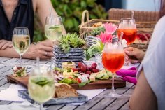 Zwei Personen sitzen an einem mit Essen gedeckten Tisch im Braustuebl und stoßen an