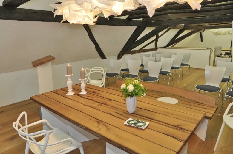 Geschmückter Trautisch im Bürgerhaus mit Blumenstrauß, Kerzen und Sitzplätzen für das Brautpaar